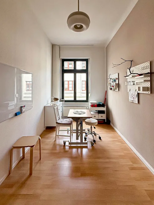Ergotherapeutischer Arbeitsplatz mit Tisch, Sitzgelegenheiten und Therapiematerial.